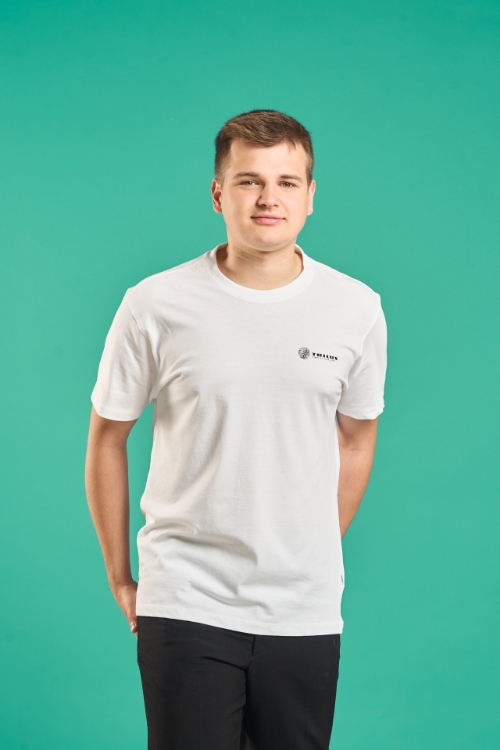 Model auf buntem Hintergrund, Trägt Jeanshose, weißes T-Shirt mit TRILUX Logo auf der linken Brust